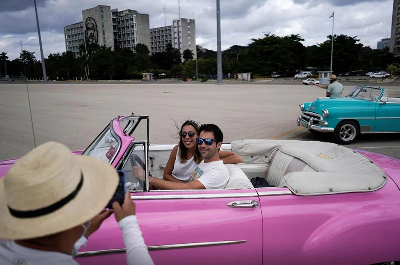 Du khách nước ngoài chụp ảnh với xe cổ tại thủ đô La Havana, Cuba. (Nguồn: Reuters)