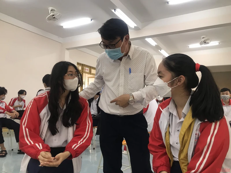 Thầy Lê Đắc Tường hỏi thăm sức khỏe các em học sinh sau khi tiêm vaccine Covid-19.