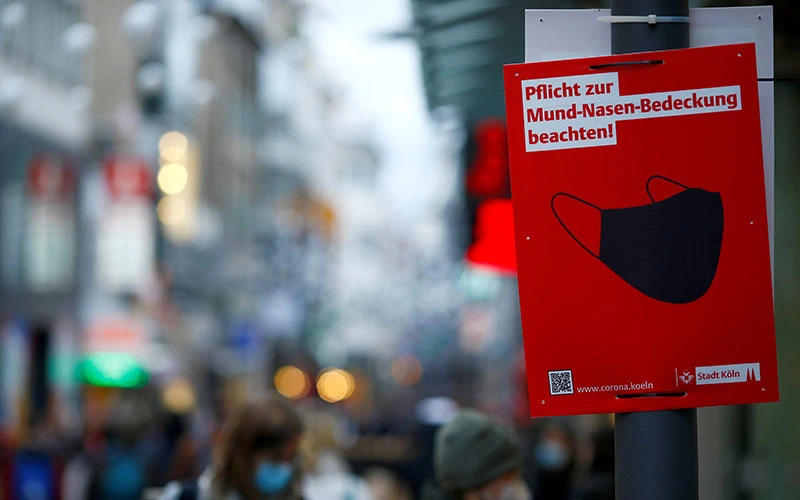 Biển nhắc nhở người dân che miệng và mũi trên phố mua sắm Strasse tại TPCologne, Đức, tháng 12/2021. (Ảnh: Reuters)