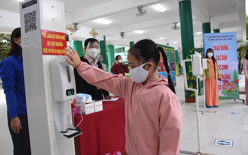 Học sinh lớp 1 Trường Tiểu học Núi Thành (Đà Nẵng) đo thân nhiệt, rửa tay sát khuẩn trước khi vào lớp.
