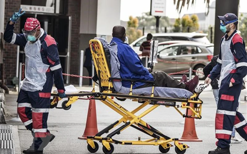 Nhân viên y tế chuyển bệnh nhân mắc Covid-19 vào 1 bệnh viện ở Port Elizabeth, Nam Phi. (Ảnh: TTXVN)