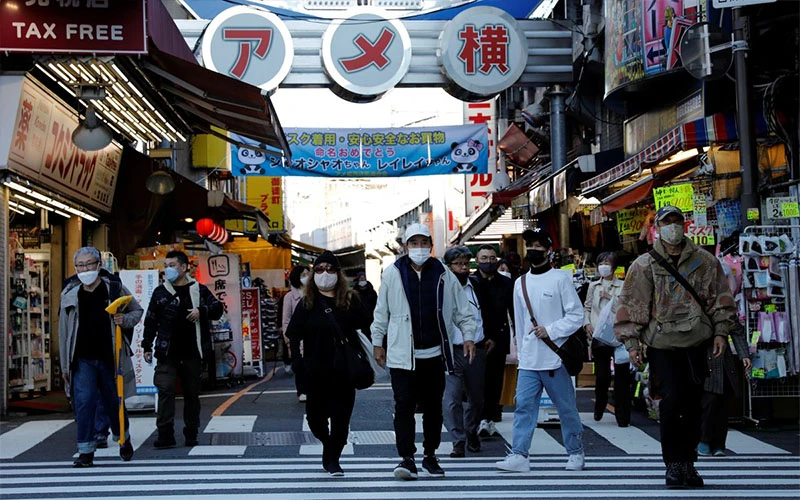 Người dân đeo khẩu trang khi đi vào phố mua sắm Ameyoko tại thủ đô Tokyo, tháng 12/2021. (Ảnh: Reuters)