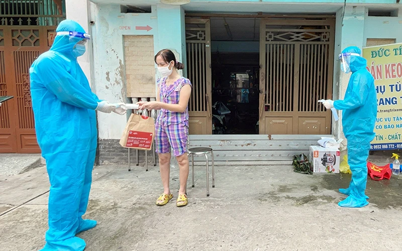 Nhân viên y tế phường 25, quận Bình Thạnh (TP Hồ Chí Minh) phát túi thuốc cho F0 điều trị tại nhà. Ảnh TTXVN
