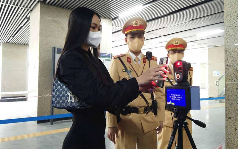 Cảnh sát giao thông Hà Nội hướng dẫn người dân thực hiện quét mã QR để khai thông tin hành khách đi tàu.