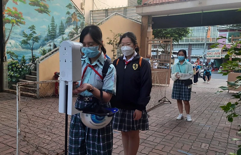 Học sinh Trường THCS Lý Phong, quận 5 đo thân nhiệt, sát khuẩn trước khi vào trường học.