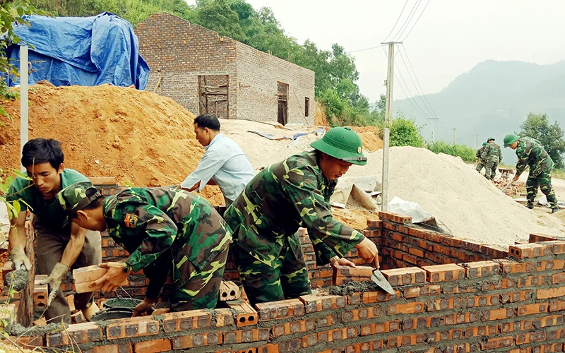 Cán bộ, chiến sĩ Ðồn Biên phòng Bản Máy hỗ trợ hộ nghèo tại xã Bản Máy, huyện Hoàng Su Phì (Hà Giang) làm nhà mới. Ảnh: KHÁNH TOÀN
