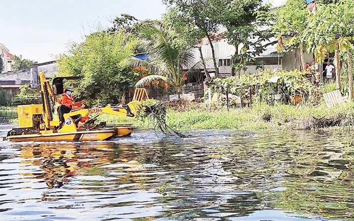 Công nhân Công ty cổ phần Công trình giao thông Sài Gòn vận hành thiết bị thu gom rác, lục bình trên sông Vàm Thuật, quận Gò Vấp.