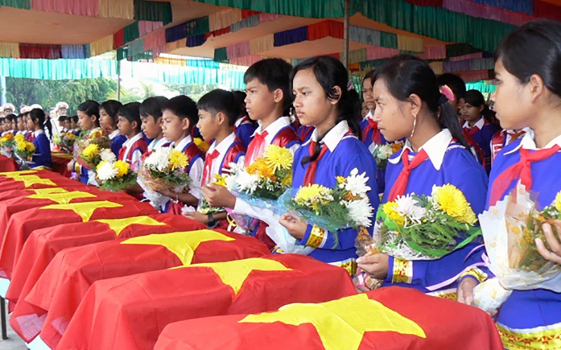 Các cháu thiếu nhi đặt hoa tưởng niệm các liệt sĩ hy sinh tại Campuchia trong lễ truy điệu và an táng hài cốt liệt sĩ ở Nghĩa trang liệt sĩ huyện Ðức Cơ (Gia Lai). Ảnh: PHAN HÒA 