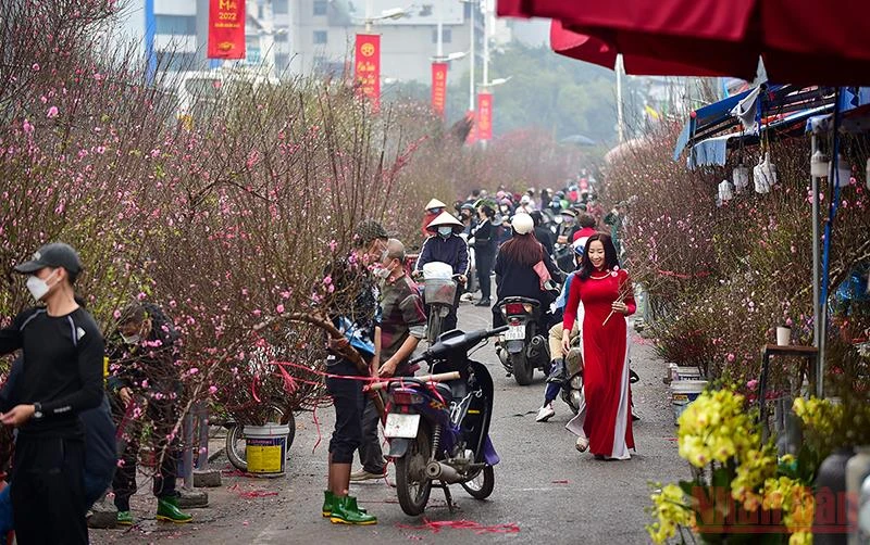 Đâu đó là hình ảnh thiếu nữ với tà áo dài đỏ đi giữa cảnh tập nập ở chợ hoa Quảng Bá. (Ảnh: Thành Đạt)