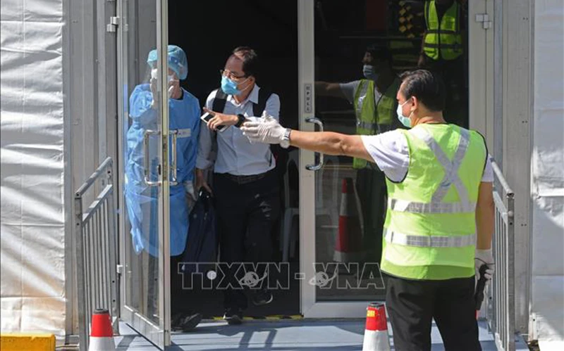 Nhân viên hướng dẫn hành khách trong chương trình Làn đi lại cho người đã tiêm vaccine (VTL), tại Singapore . (Ảnh: THX/TTXVN)
