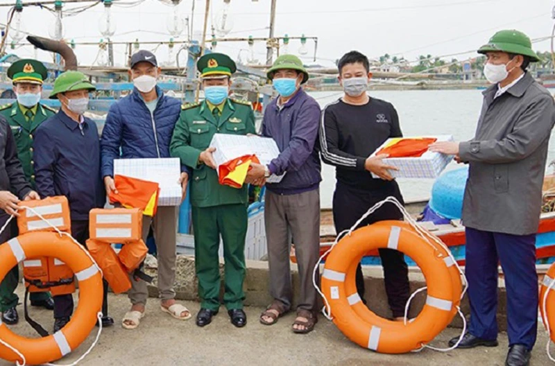 Chủ tịch tỉnh Quảng Bình Trần Thắng (bên phải) tặng quà và cờ Tổ quốc cho ngư dân.