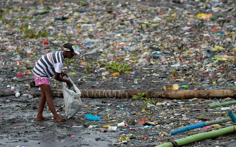 Một người phụ nữ nhặt những chiếc cốc nhựa bị vứt ra ngoài môi trường dọc bờ sông Pasig ở Manila, Philippines, ngày 10/6/2021. (Ảnh: Reuters)