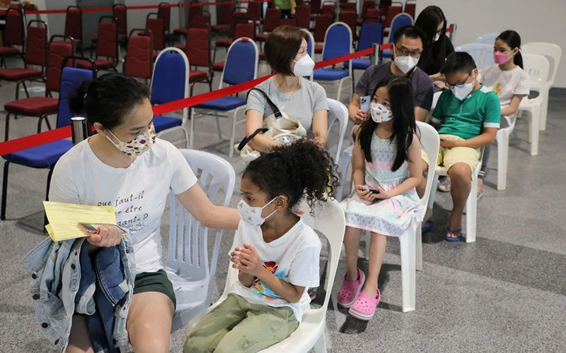 Cha mẹ đi cùng trẻ 5-11 tuổi khi tiêm phòng vaccine ngừa Covid-19 tại Kuala Lumpur, Malaysia. Ảnh: Reuters