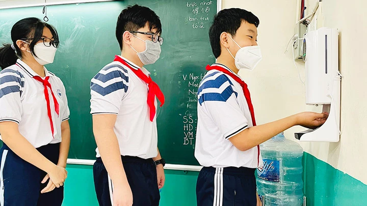 Học sinh Trường THCS Nguyễn Du ở quận 1, TP Hồ Chí Minh khử khuẩn, đo thân nhiệt trước khi vào bàn học.