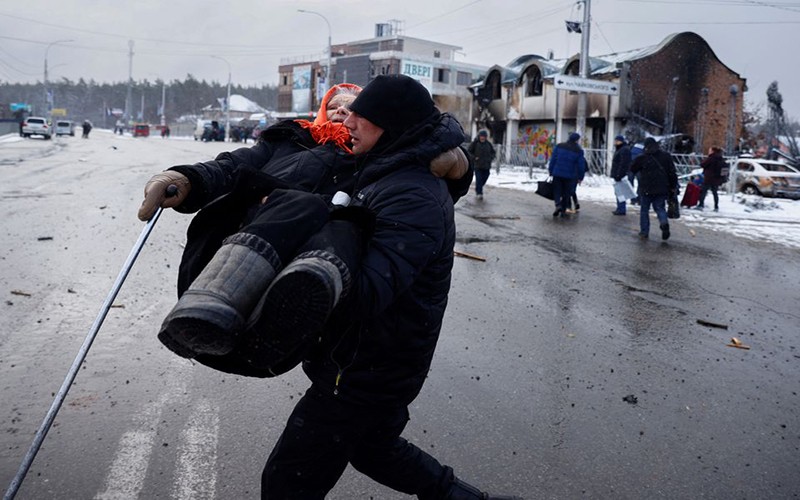 Người đàn ông đưa cụ già rời khỏi khu vực Irpin, gần thủ đô Kiev, Ukraine, ngày 8/3. (Ảnh: Reuters)