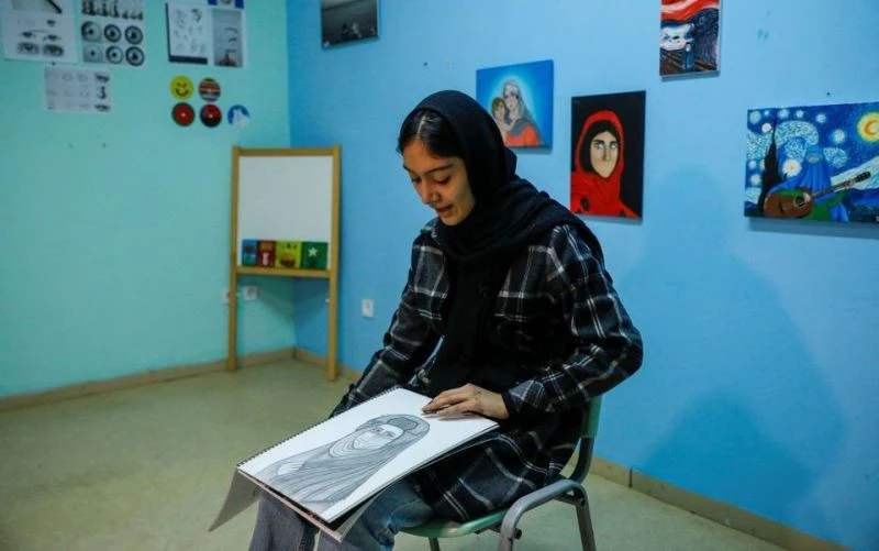 Roya Rasuli giới thiệu một trong những bức vẽ của cô tại trại tị nạn Thiva, Hy Lạp, ngày 3/3/2022. (Ảnh: REUTERS)