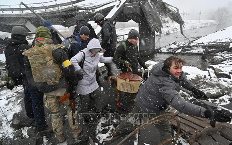 Binh sĩ Ukraine hỗ trợ người sơ tán khỏi thành phố Irpin, phía Tây Bắc thủ đô Kiev ngày 8/3. (Ảnh: AFP/TTXVN)