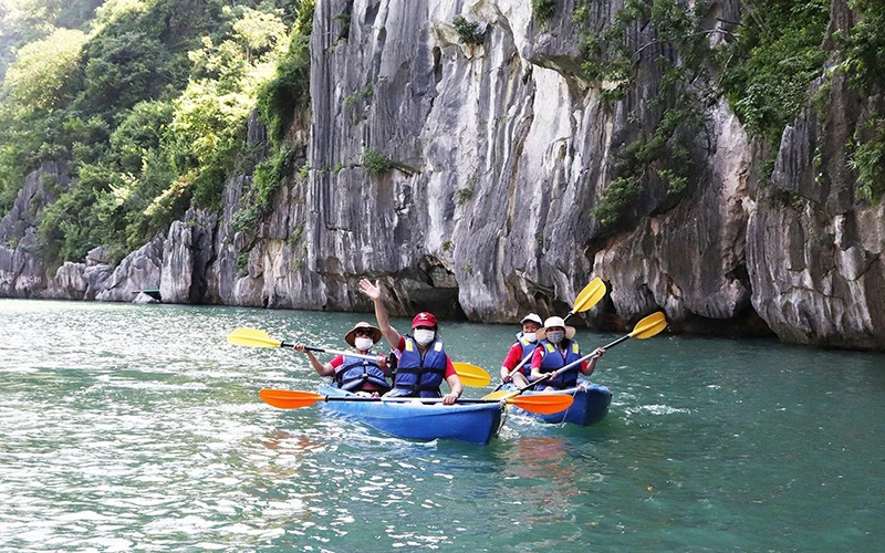 Khách du lịch quốc tế trong tour du lịch tham quan chèo thuyền kayak tại Vịnh Hạ Long. (Ảnh NGHĨA HIẾU)