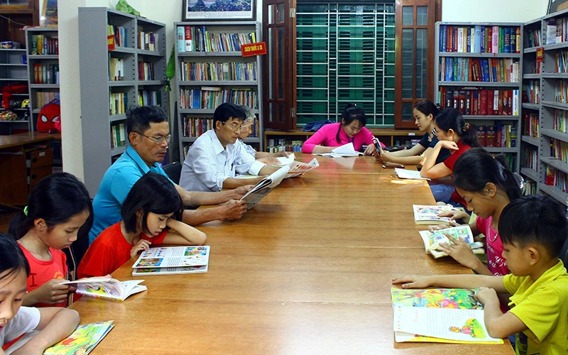 Học sinh cùng người dân xã Kim Liên đọc sách, báo tại Thư viện Làng Sen, huyện Nam Đàn, Nghệ An. (Ảnh TTXVN)