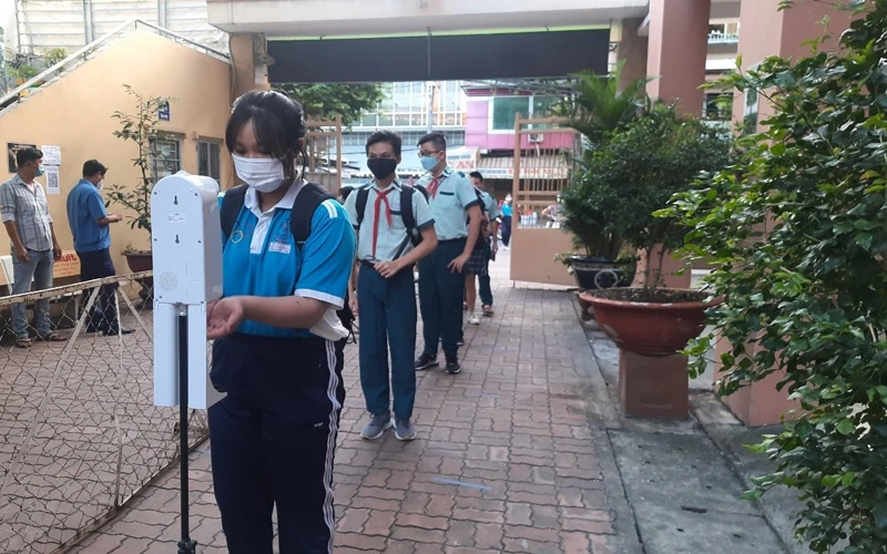 Học sinh tại Thành phố Hồ Chí Minh kiểm tra thân nhiệt, sát khuẩn tay trước khi vào lớp học.