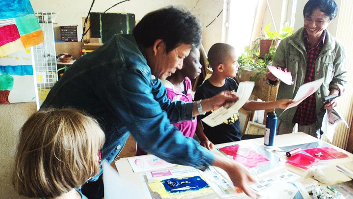 Họa sĩ Đỗ Đức và họa sĩ Lê Huy Tiếp hướng dẫn trẻ nước ngoài tập in tranh. Ảnh: Họa sĩ cung cấp