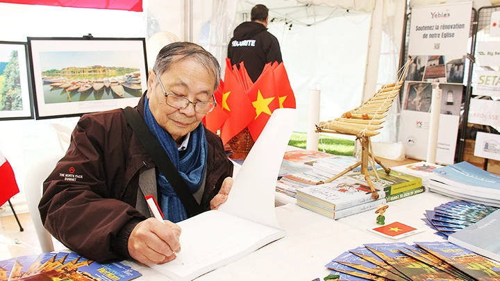 Ông Nguyễn Thanh Tòng ký tặng sách ảnh “Biển đảo quê hương” tại Ngày hội Pháp ngữ ở Pháp, 19-20/3/2022.