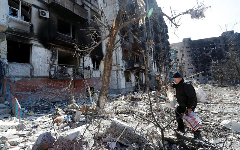 Người đàn ông đi qua sân của một tòa chung cư tại TP Mariupol, Ukraine, ngày 28/3. (Ảnh: Reuters)