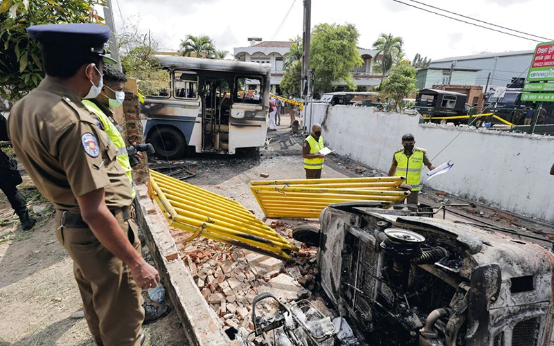 Cảnh sát làm việc tại hiện trường xe ô-tô bị phóng hỏa trên đường dẫn tới nơi ở của Tổng thống Rajapaksa. (Ảnh: Reuters)