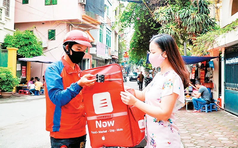 Nhân viên một sàn thương mại điện tử giao hàng cho khách. (Ảnh NGỌC CHÂU) 