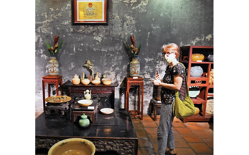 Khách du lịch tham quan khu trưng bày các sản phẩm gốm tại Ðình Kim Ngân. (Ảnh ÐĂNG DUY)
