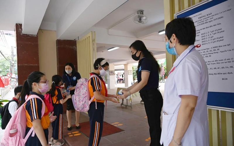 Học sinh Trường tiểu học Thăng Long (Hoàn Kiếm, Hà Nội) rửa tay sát khuẩn, kiểm tra thân nhiệt trước khi vào trường học trực tiếp. (Ảnh: Duy Linh)