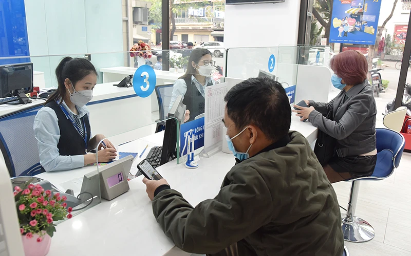 Giao dịch viên Ngân hàng TMCP Bảo Việt tư vấn, hướng dẫn khách hàng trước khi mở tài khoản ngân hàng. (Ảnh ANH ĐỨC)