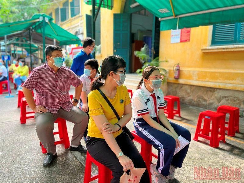 Phụ huynh và trẻ chờ đến lượt tiêm tại điểm trường THCS Hồng Bàng.