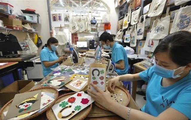 Người khuyết tật sáng tạo các tác phẩm thủ công tại Hợp tác xã Vụn Art ở Hà Đông (Hà Nội). (Ảnh: Minh Quyết/TTXVN)