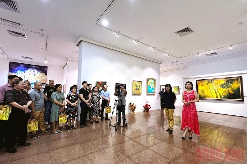 Hoạ sĩ Trần Thảo Hiền (váy hồng) giới thiệu với khách tham quan về triển lãm.