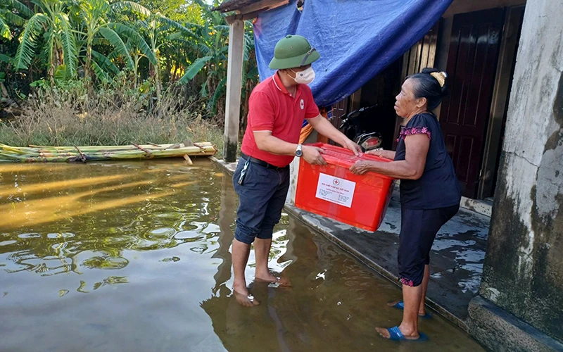 Đại diện Hội Chữ thập đỏ tỉnh Quảng Bình trao thùng hàng hỗ trợ hộ dân bị ảnh hưởng mưa, lũ tại xã Tân Ninh, huyện Quảng Ninh. (Ảnh PHƯƠNG DUNG)