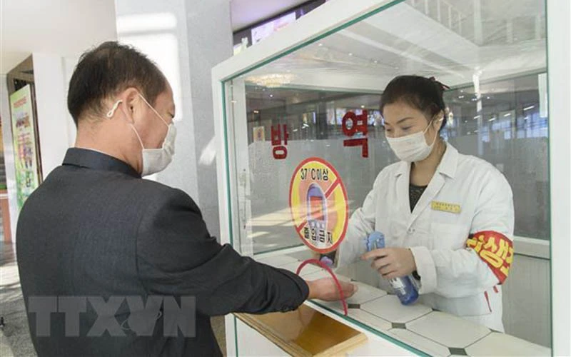 Khử khuẩn tay, đo thân nhiệt, nhằm ngăn chặn sự lây lan của dịch Covid-19 trước khi vào trung tâm thương mại ở Bình Nhưỡng, Triều Tiên. (Ảnh: AFP/TTXVN)