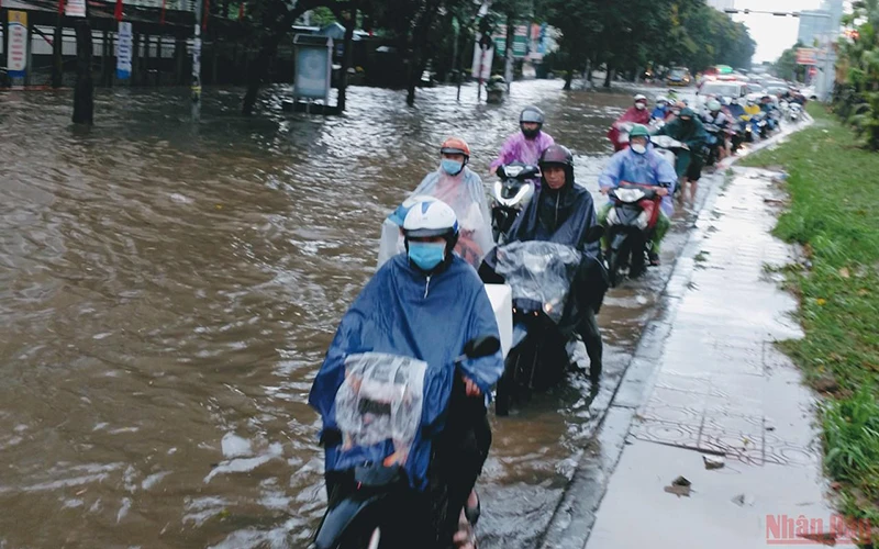 Người tham gia giao thông di chuyển khó khăn trên đường Hoàng Quốc Việt (Hà Nội) sau trận mưa lớn chiều 28/5. (Ảnh: Đăng Khoa)
