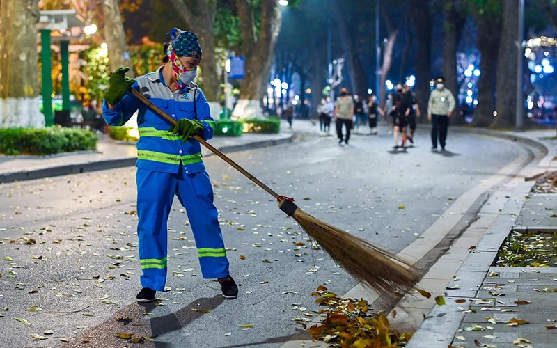 Công nhân môi trường đô thị Hà Nội dọn vệ sinh tại khu vực tuyến phố đi bộ hồ Hoàn Kiếm. (Ảnh VIỆT LINH)