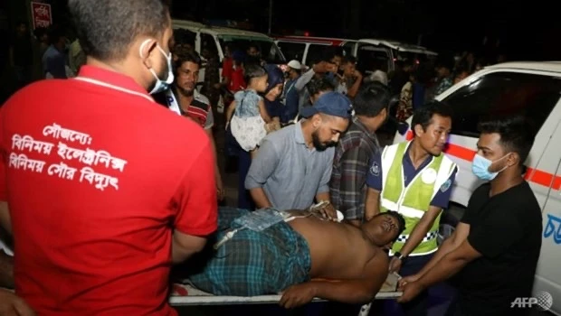 Các nhân viên cứu hộ và dân thường khiêng một nạn nhân bị thương tới bệnh viện ở Chittagong, Bangladesh, sau khi đám cháy lớn bùng phát tại một kho cảng container địa phương. (Nguồn: AFP/Vietnam+)