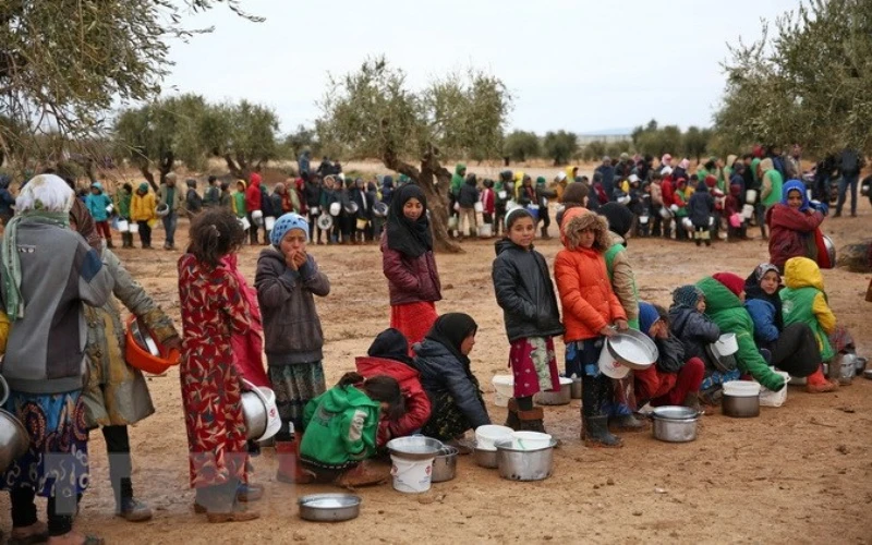 Người dân xếp hàng chờ được phát lương thực cứu trợ tại trại tị nạn ở Yazi Bagh, Aleppo, Syria. (Ảnh: AFP/TTXVN)