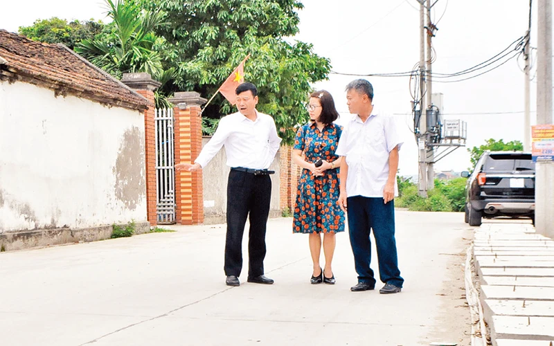 Anh Ðỗ Văn Thang (người bên trái) giới thiệu con đường ven làng Mây (thôn Thanh Vân) do chính quyền và nhân dân cùng góp công, góp sức xây dựng. 