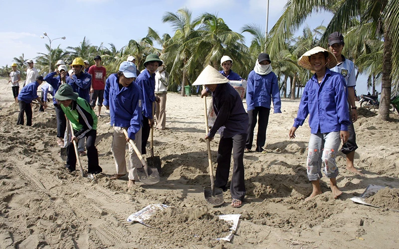 Đoàn viên thanh niên và người dân làm sạch môi trường biển tại thành phố Hội An, tỉnh Quảng Nam. (Ảnh NGUYỄN ĐĂNG)