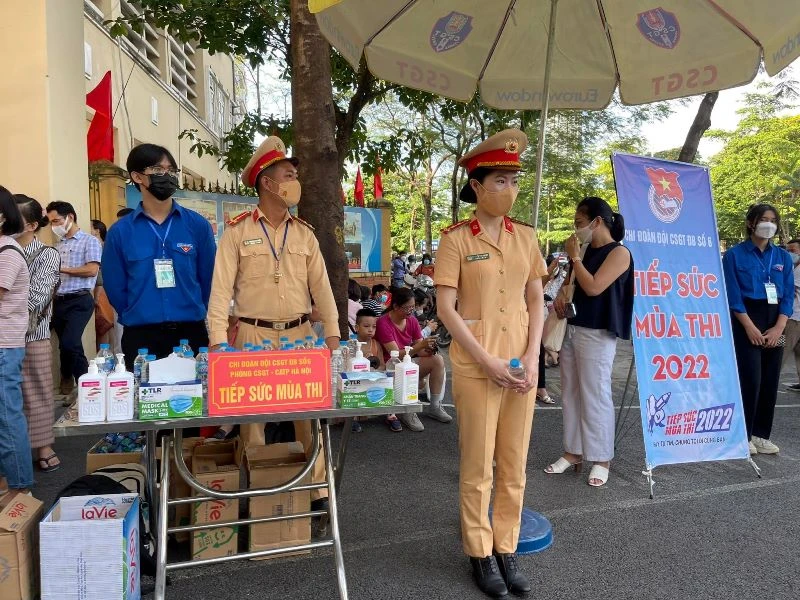 Nữ cảnh sát giao thông thuộc Đội Cảnh sát giao thông số 6 (Phòng Cảnh sát giao thông Hà Nội) phát nước và bút cho các em thí sinh.