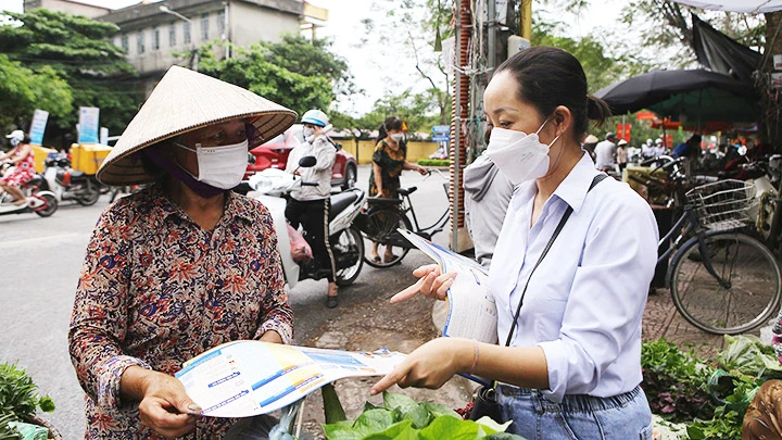 Phát tờ rơi vận động người dân tham gia bảo hiểm xã hội tự nguyện, bảo hiểm y tế tại Nam Định. Ảnh: TTXVN