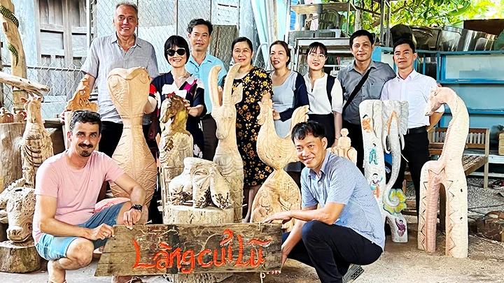 Lê Ngọc Thuận (người ngồi bên phải) giới thiệu sản phẩm mỹ nghệ cho khách du lịch.