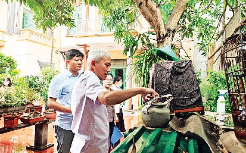 Người dân thôn Nhuế, xã Kim Chung, huyện Đông Anh kiểm tra các dụng cụ chứa nước để loại trừ bọ gậy. (Ảnh Khánh Hà)