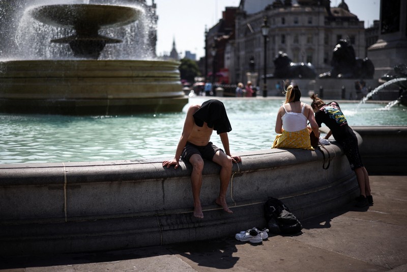 Người dân giải nhiệt cạnh đài phun nước Quảng trường Trafalgar trong đợt nắng nóng kỷ lục, London, Anh, ngày 19/7/2022. (Ảnh: REUTERS)