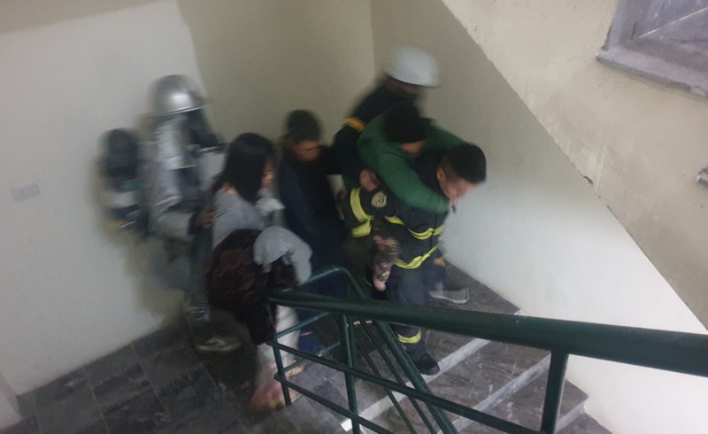 Cảnh sát phòng cháy, chữa cháy cõng cụ già thoát khỏi vụ hỏa hoạn theo cầu thang bộ. (Ảnh: Công an cung cấp)