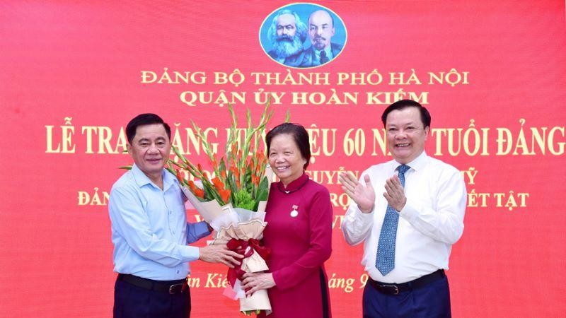 Chủ nhiệm Ủy ban Kiểm tra Trung ương Trần Cẩm Tú và Bí thư Thành ủy Hà Nội Đinh Tiến Dũng tặng hoa chúc mừng đồng chí Nguyễn Thị Xuân Mỹ.